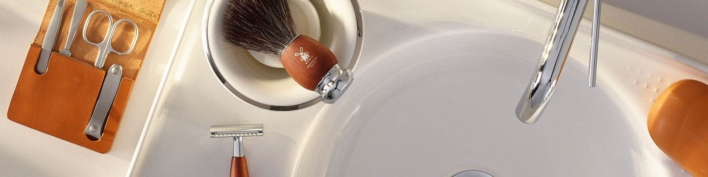 Bathroom sink with grooming tools including a MÜHLE  VIVO brush, razor, and manicure set.