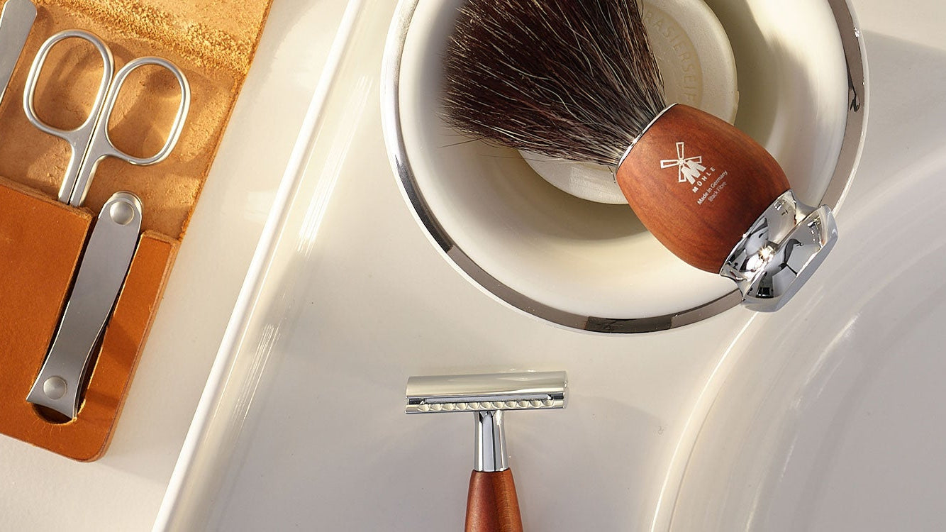Bathroom sink with grooming tools including a MÜHLE  VIVO brush, razor, and manicure set.